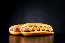 Two Hotdogs With Big Sausage And Mustard Isolated On Black Background. Front View.