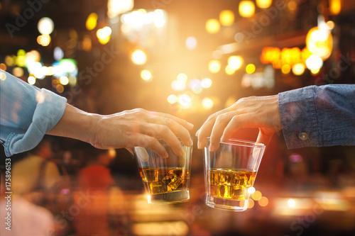 Fotografía Cheers clinking of friends with bourbon whiskey drinks in party night after work