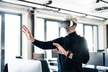 Mature businessman with VD goggles in the office.