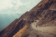 © ra66 - Spectacular and dangerous mountain road, Tusheti, Georgia. Adventure concept. Mount landscape. Unpaved winding road. Dirt serpentine road. Sunlight rays. Explore the world. Travel to Caucasus. Autumn