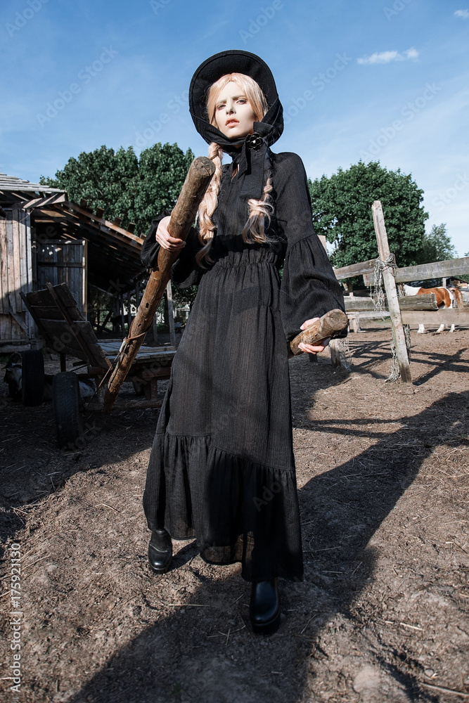 Fashion young woman wearing stylish black dress and hat at countryside.  Amish fashion style. Stock Photo | Adobe Stock