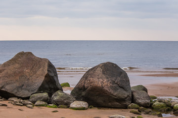 A beautiful landscape of a beach with stones. Baltic sea shore with rocks. An autumn scenery at the sea.