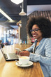 © santypan - Beautiful afro american woman using mobile and laptop in the coffee shop.