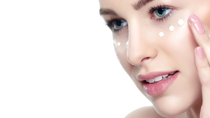 Wall Mural - beautiful young blond woman applying face cream under her eyes. facial treatment. cosmetology, beaut