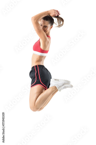 Fotografia Profile of fit active ecstatic young sportswoman jumping in mid air frozen motion