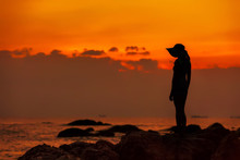 Silhouette Of A Girl In A Hat Against The Background Of An Orange Sea Sunset.  End Of The Earth. Hainan, China.