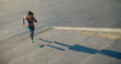© Jacob Lund/Stocksy - Panoramic crop of female jogger running on stairs