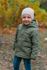 boy in green jacket in yellow red park autumn