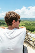 © AlejandroMCB photo & film/Stocksy - Back view of a young man contemplating the green landscape at a lookout of ruins