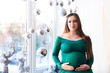 © Nestyda - Beautiful pregnant girl with Big belly near the window on a Christmas, having a rest on Christmas holidays before the new year. the concept of a new life