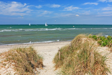 Wall Mural - Weg durch Dünen zum Strand an der Ostsee mit blauem Himmel mit Wolken bei Heiligenhafen, Schleswig-Holstein. Mit Segelbooten, Kitesurfern und Möwen.