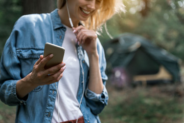 Wall Mural - Happy young woman listening to music in forest