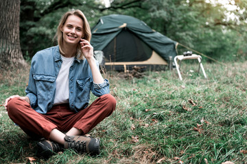 Wall Mural - Joyful young woman sitting on grass in the nature