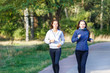 © skumer - Two young smiling woman jogging in park in the morning