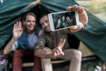 Wall Mural - Happy tourists making selfie on smartphone in tent