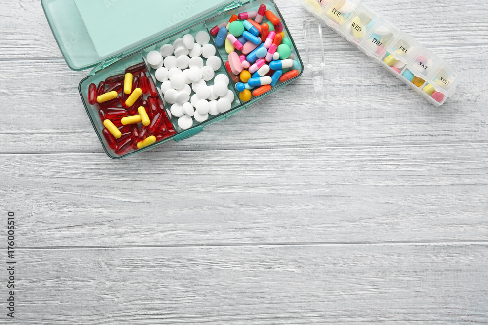 Plastic containers with different pills on wooden background