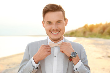 Wall Mural - Handsome groom in wedding suit on beach