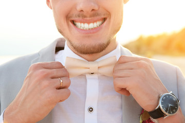 Wall Mural - Handsome groom in wedding suit on beach, closeup