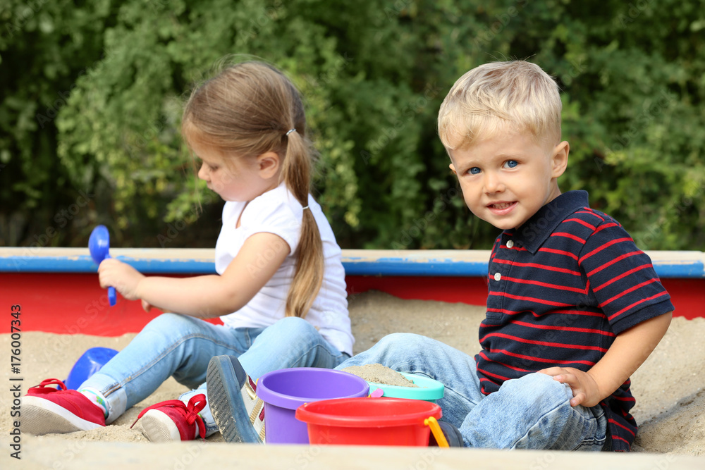Cute little children playing in  sandbox, outdoors