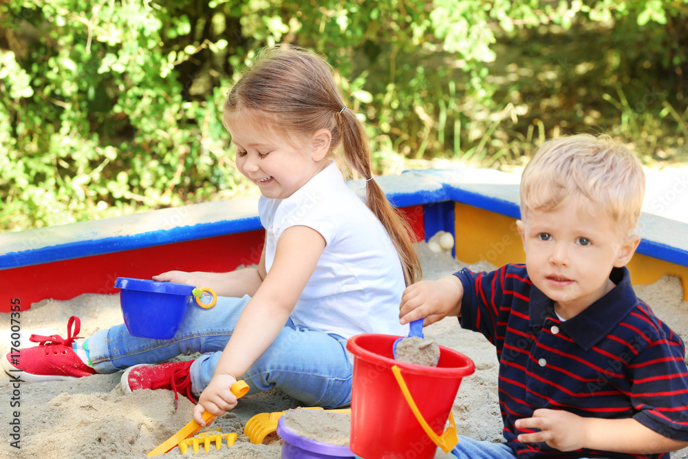 Cute little children playing in  sandbox, outdoors