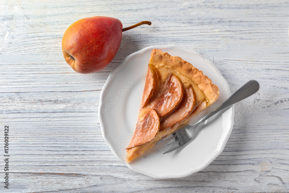 Plate with tasty pear tart on white wooden table