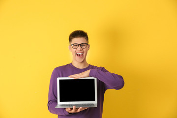 Wall Mural - Teenager boy with laptop on color background