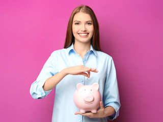 Sticker - Beautiful young woman with piggy bank on color background