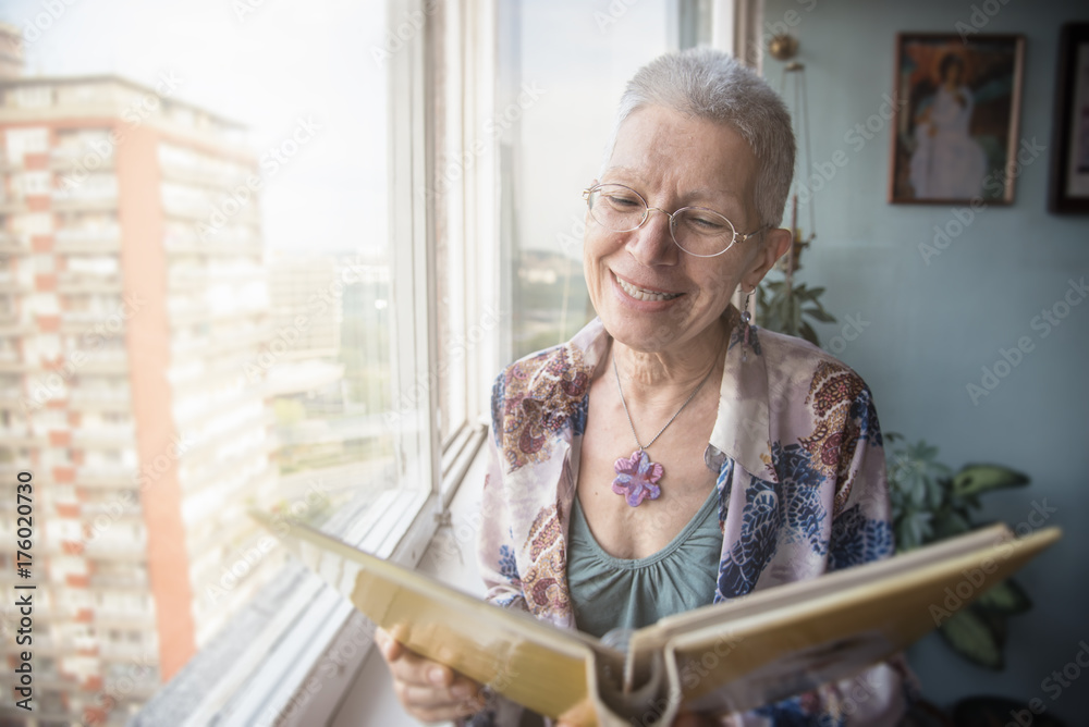 Senior elderly lady looking at some old photos in a photo album ...