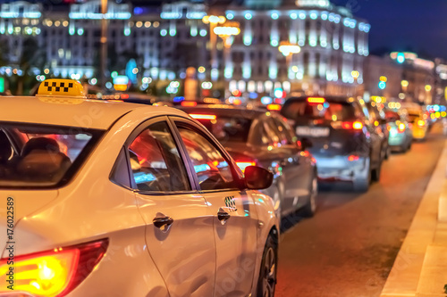 Plakat taksówka w korku na tle świateł miasta nocą i bokeh