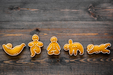 Gingerbread cookies in shape of yoga asanas on dark wooden background top view copyspace