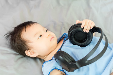 Canvas Print - Portrait of adorable baby lying on the bed with headphone, indoors