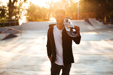 Wall Mural - Smiling male teenager guy holding skateboard