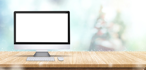 Fototapete - Blank screen computer desktop on wooden table with abstract blur christmas tree and snow falling background with bokeh,Holiday backdrop,Mock up banner for display of product for promotion online.