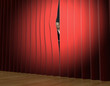 woman looking through theatre curtains on stage