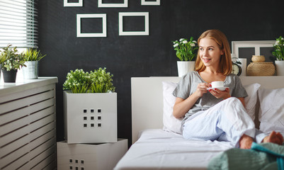 Poster - happy young woman with cup of morning coffee in bed