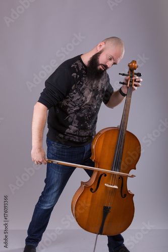 Plakat Wiolonczelista grający muzykę klasyczną na wiolonczeli. Brodaty mężczyzna wygłupia się z instrumentem muzycznym