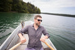 © Gonzales Photo - A man is rowing a rowboat on a lake.