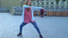 Young Attractive Woman Professional Dancer Contemporary Dance Dancing On A Square In The Street. Modern Extreme Dances In The Style Of Hip-hop And Classical Ballet. The Girl Rhythmically Moves To The