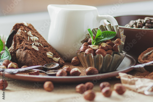 Plakat Kawałek ciasto czekoladowe, liści mięty, orzechy laskowe i słoik z mlekiem