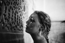 A Young Woman Gazes Through A Carved Screen In A Historical Building.