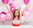 © Ermolaev Alexandr - Happy girl in party hat with birthday cake lifted her arms in joy