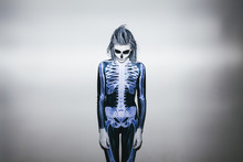 Young Woman With Skeleton Costume And Halloween Make Up Against White Wall