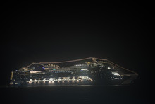 A Huge Cruise Ship At Night Stands At Anchor Glowing With Very Bright Lights