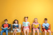 © Africa Studio - Cute little children reading books while sitting near color wall