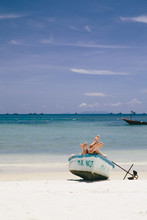 Couple Lying In Boat On The Tropical Beach