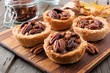 Mini pecan pie tarts, close up scene on a wooden server against a rustic wood background