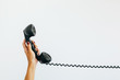 © Kelly Knox/Stocksy - woman's hand holding a vintage telephone  with cord stretched out