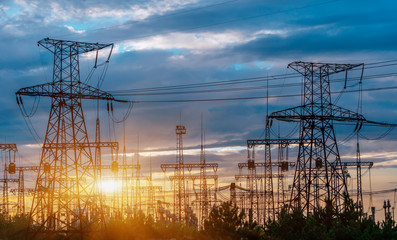 distribution electric substation with power lines and transformers, at sunset.