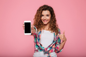 Young cheerful caucasian lady showing smartphone with blank screen isolated