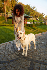 Wall Mural - Full-length shot of pretty healthy young lady walking in the morning in park with dog